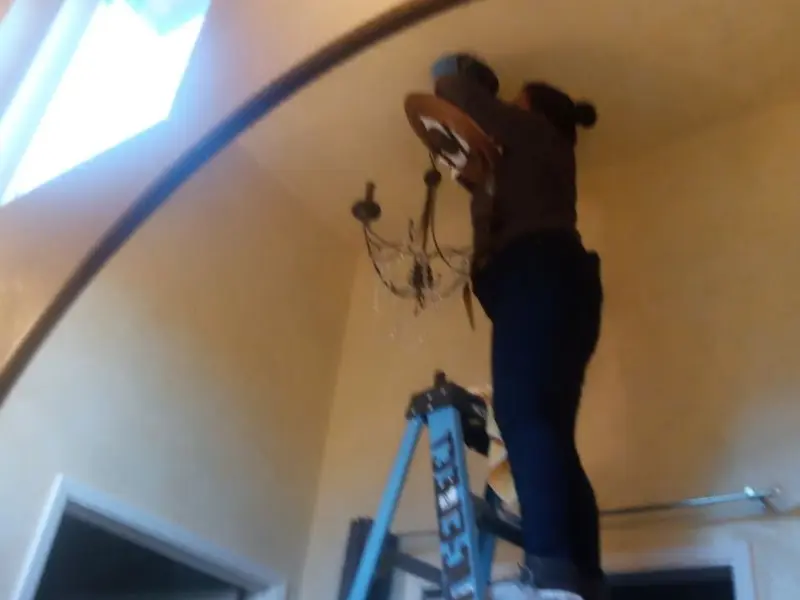 Electrician installing a chandelier in a Princeton residence